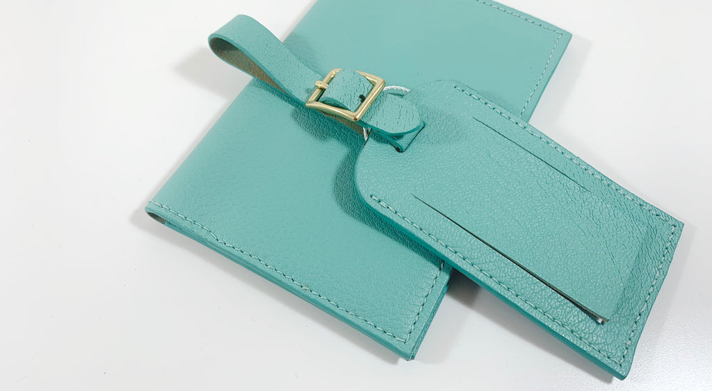 Mint colored luggage tag laying across a matching passport case