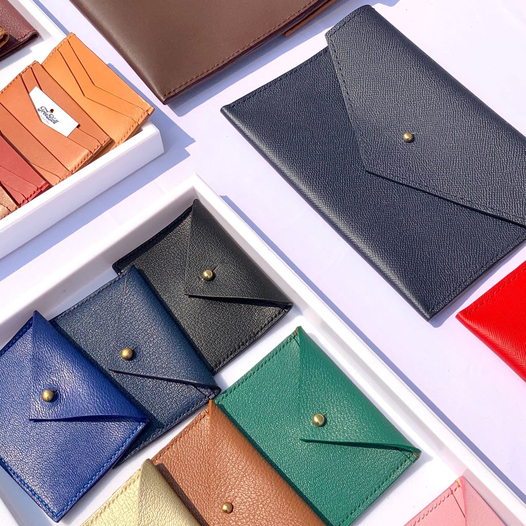 Leather wallets in various colors displayed on white table.